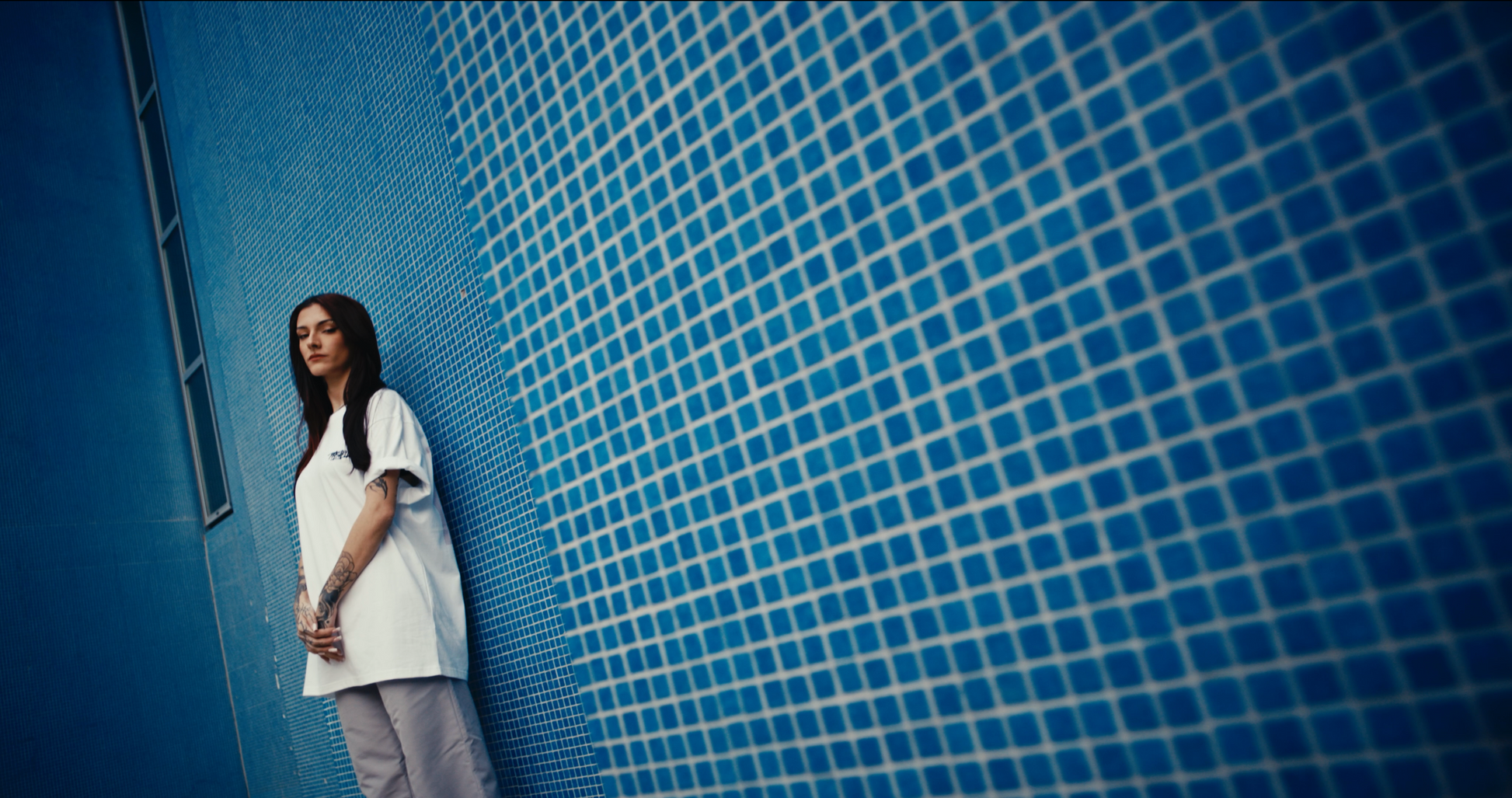 oversized white ELLEX PASTELLE tee with black embroidered logo on front with blue tiled backdrop