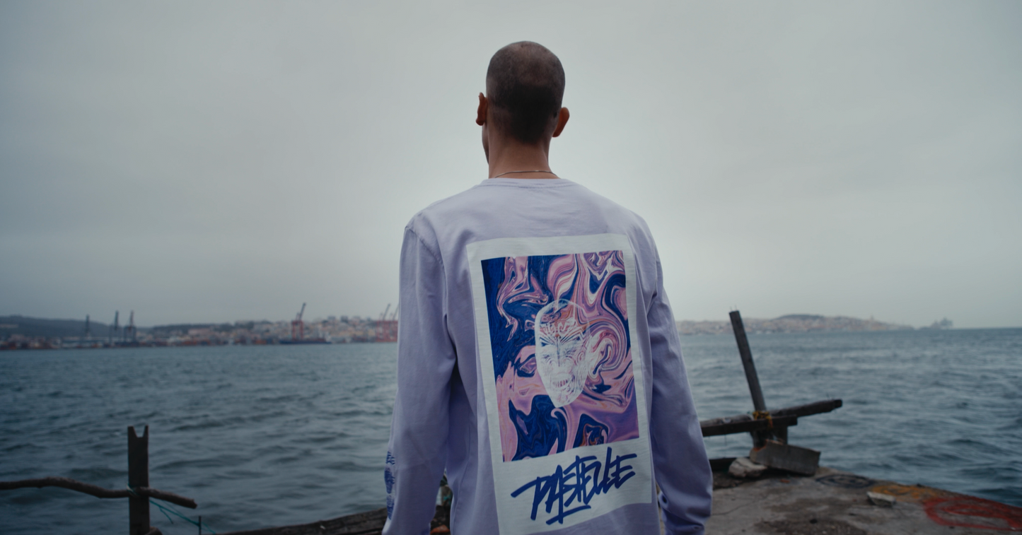 back shot of violet VOODOO PASTELLE oversized longsleeve on 185cm model with Lisbon Tejo river in the background