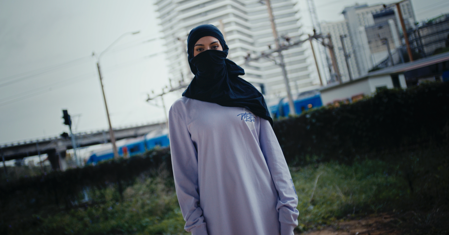 violet oversized VOODOO PASTELLE longsleeve tee on 165cm female model wearing baclava in trainyard background