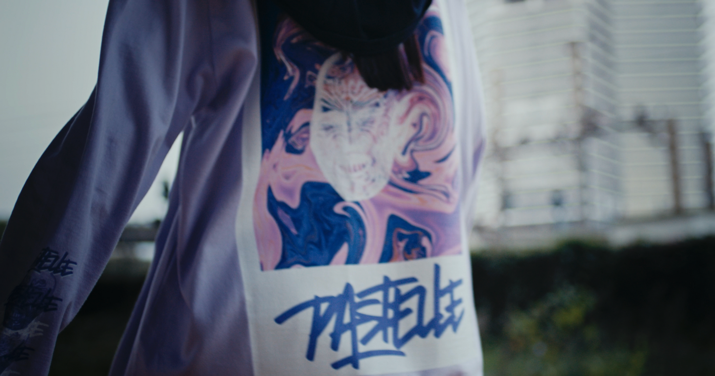 lower view closeup of violet oversized VOODOO PASTELLE longsleeve tee on 165cm female model wearing baclava in trainyard background