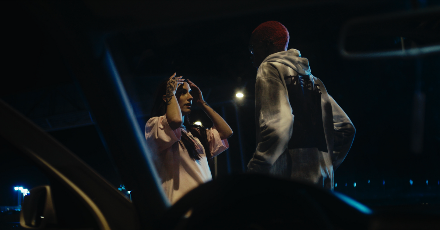 night shot of salmon coloured daydreaming box fit oversized PASTELLE tee on female 165cm model alongside male 185cm model wearing a PASTELLE hoodie
