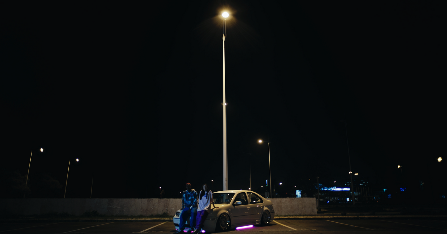 long distance night shot of salmon coloured daydreaming box fit oversized PASTELLE tee on female 165cm model alongside male 185cm model wearing a PASTELLE hoodie