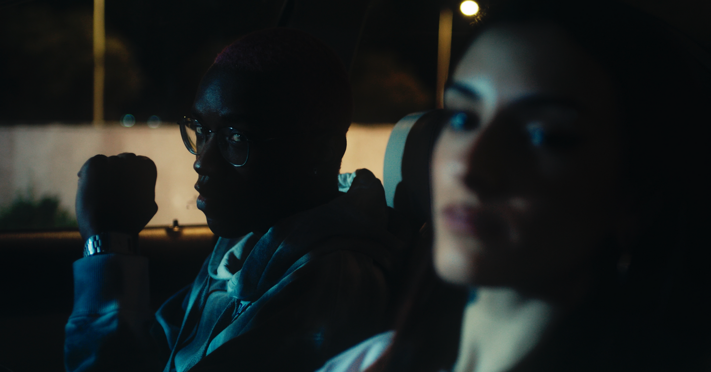 inside car shot at night of salmon coloured daydreaming box fit oversized PASTELLE tee on female 165cm model alongside male 185cm model wearing a PASTELLE hoodie