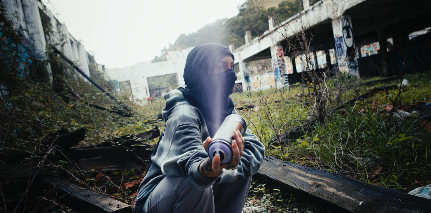 female model wearing PASTELLE hoodie spraying spray can in air